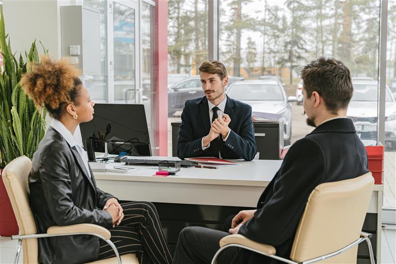 Home loan options discussion A business meeting with a man and woman discussing with a male representative at a desk.